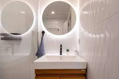 a white bathroom with a sink and two mirrors at Private 4BR Model Home center Patong in Patong Beach