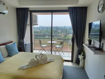 a bedroom with a bed and a balcony with a table at Heavenly place 777 on Mai Khao in Ban Mai Salae