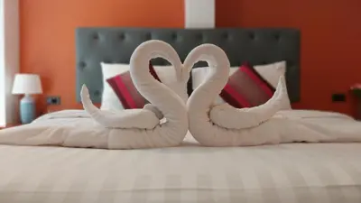 two swans shaped like hearts are sitting on a bed at Benetti house in Patong Beach