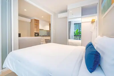 a white bed with blue pillows in a bedroom at Pool Access Condo Bangtao Beach in Bang Tao Beach