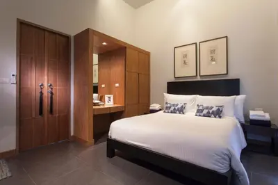 a bedroom with a large bed and a wooden cabinet at Wings Phuket Villa by Two Villas HOLIDAY in Bang Tao Beach