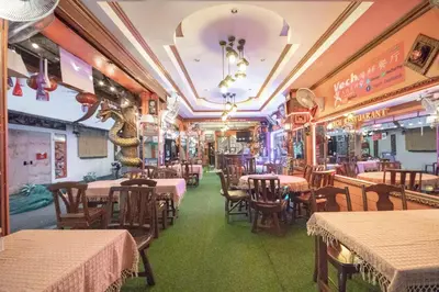 a restaurant with tables and chairs in a room at Vech Guesthouse Patong in Patong Beach