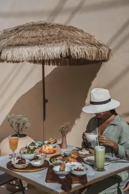 a woman in a hat sitting at a table with food at Casa Solana Patong in Patong Beach