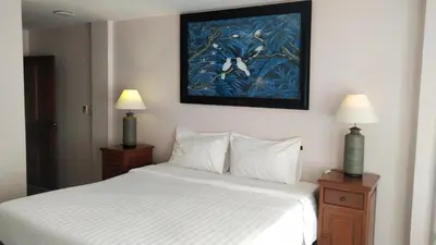 a bedroom with a bed with two lamps and a painting on the wall at Rendez Vous Hotel in Patong Beach