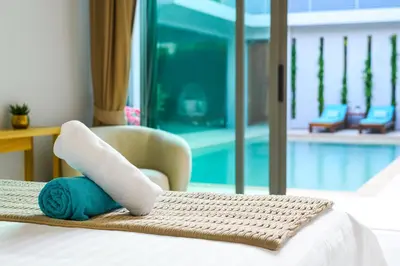 a hotel room with a bed with a towel and a chair at Villa Mimosa 1, Luxury 4BR with Private Pool/Rawai in Phuket Town