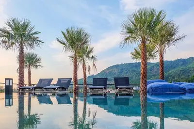 a swimming pool with palm trees and lounge chairs at Tropics Kamala Deluxe Pool View Apartment CTG P402 in Kamala Beach