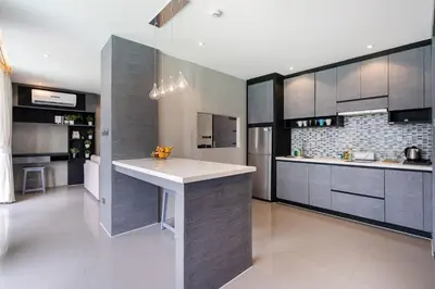 a kitchen with gray cabinets and a white counter top at Tropics Kamala Deluxe Pool View Apartment CTG P402 in Kamala Beach