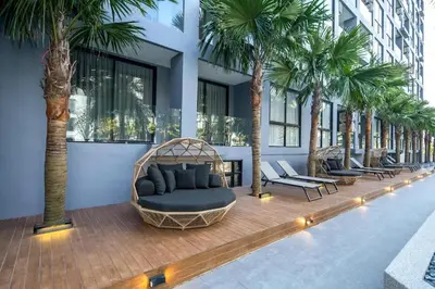 a room with a couch and palm trees in a building at Tropics Kamala Pool View Residence CTG B704 in Kamala Beach