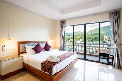 a bedroom with a bed and a large window at Tri's Miracle Kata Beach Side in Kata Beach