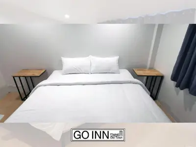 a bedroom with a white bed with two tables at xx GO INN Phuket Old Town ภูเก็ตโอลทาวน์ ย่านเมืองเก่า in Phuket Town