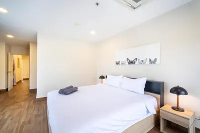 a white bedroom with a large bed and a lamp at Patong tower Superior Seaview 4BR-2102 in Patong Beach