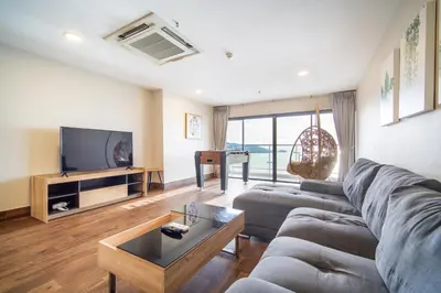 a living room with a couch and a tv at Patong Tower Superior Seaview 4BR-2101 in Patong Beach