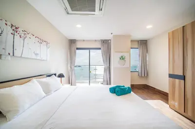 a bedroom with a large white bed with a window at Patong Tower Superior Seaview 4BR-2101 in Patong Beach