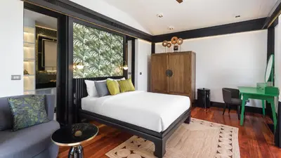 a bedroom with a bed and a couch and a desk at Villa Purissara in Phuket Town