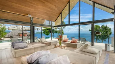 a living room with large windows and a view of the ocean at Villa Saengootsa in Phuket Town