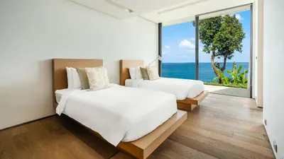 two beds in a room with a view of the ocean at Villa Saengootsa in Phuket Town