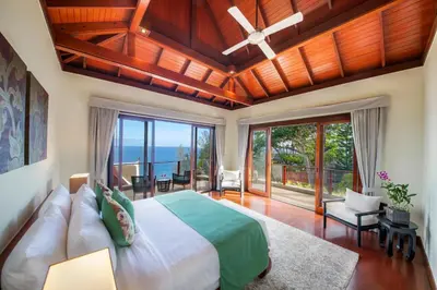 a bedroom with a large bed and large windows at Villa Horizon in Phuket Town