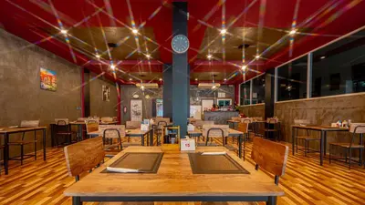 a restaurant with a large wooden table and chairs at Nice to meat you Rooms in Patong Beach