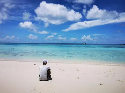 a man sitting on a beach looking at the ocean at Recommend a warm Thai style private swimming pool villa with convenient traffic and living, walking 700 meters to the the beach in Kamala Beach