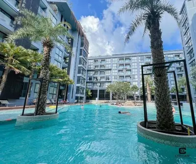 a swimming pool with palm trees in front of a building at Citygate in Kamala beach - Perfect Stay for Digital Work in Kamala Beach