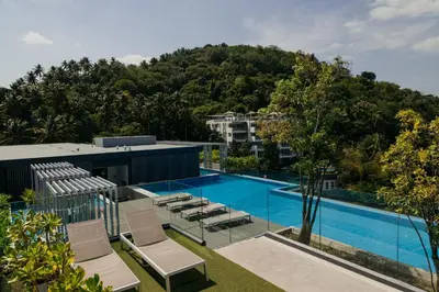an image of a swimming pool with chairs and trees at Aristo 2 Phuket, Surin beach in Surin Beach