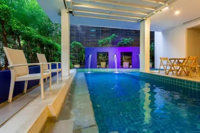 a swimming pool in a house with chairs around it at Coco boutique hotel in Patong Beach