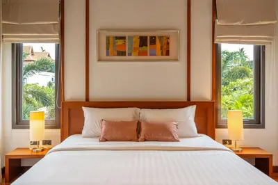 a bedroom with a bed with two lamps and two windows at Villa Autjima krabi /3BRD in Ban Khlong Haeng