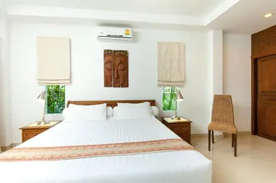 a bedroom with a white bed and two windows at Romanee Villa by G Estate in Rawai Beach