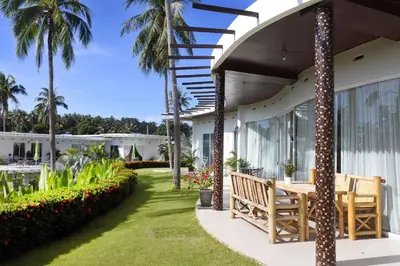 a patio with a wooden bench and palm trees at The Inspiration Residence in Rawai Beach
