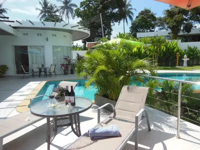 a patio with a table and chairs next to a swimming pool at The Inspiration Residence in Rawai Beach