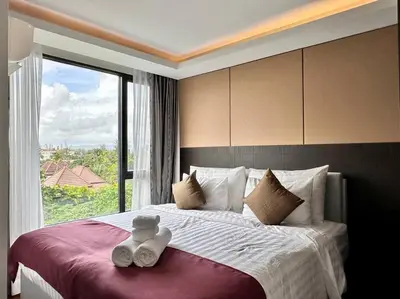 a bedroom with a large bed with a large window at Aristo Resort Surin Beach M47 in Phuket Town