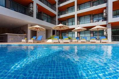 a swimming pool in front of a hotel with chairs and umbrellas at 1 bed Corner apartment in Kata - Grand Kata VIP in Kata Beach