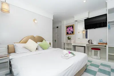 a bedroom with a large white bed and a kitchen at Patong Social Hotel & Restaurant in Patong Beach