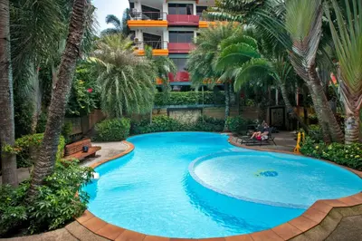 an overhead view of a large swimming pool with palm trees at 1bdr apartment NaiHarn Beach condo by Capital Pro in Phuket Town