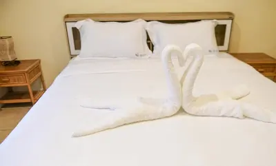 two towels shaped like swans sitting on a bed at Shimmer Three-Bedroom Villa with large garden and two swimming pools in Rawai Beach