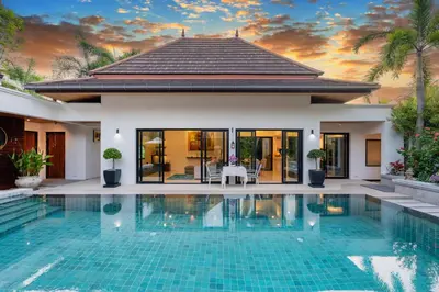 a villa with a swimming pool in front of a house at The Thara Villa Surin Beach in Surin Beach