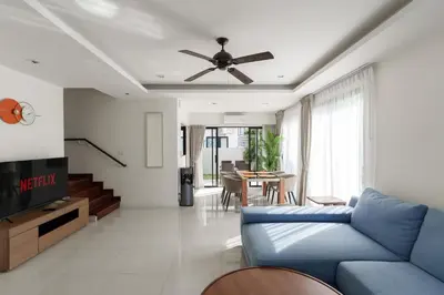 a living room with a blue couch and a ceiling fan at Welcoming 3bdr Townhouse Laguna Park in Ban Phru Champa