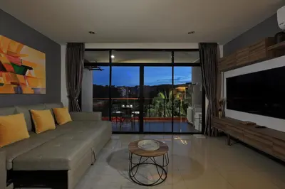a living room with a couch and a flat screen tv at 1bdr Spacious Studio near NaiHarn Beach by Capital Pro in Phuket Town