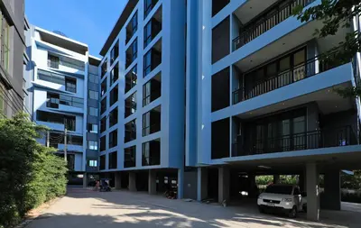 a blue apartment building with a car parked in front at 1bdr Apartment ReLife Windy Naiharn by CapitalPro in Phuket Town