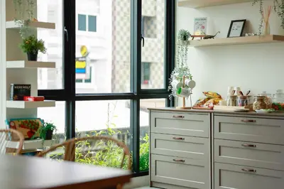 a kitchen with white cabinets and a table at Chamemon Bed Phuket Town in Phuket Town