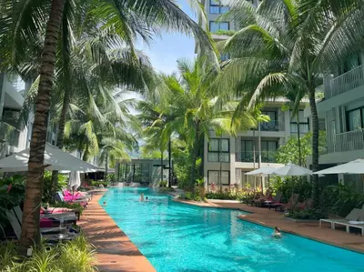 a swimming pool with palm trees and buildings at Mountain view apartment in the heart of BangTao in Bang Tao Beach