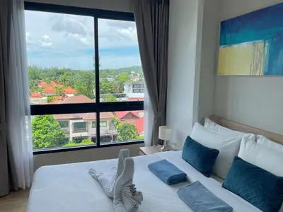 a bedroom with a bed with a large window at Mountain view apartment in the heart of BangTao in Bang Tao Beach