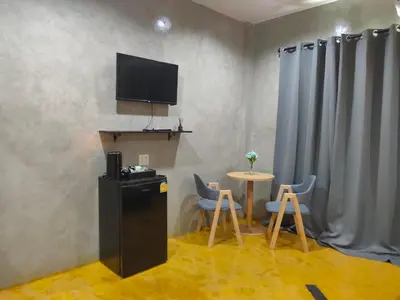 a room with a small table and a television on the wall at Phudis Guest House in Ban Khlong Haeng