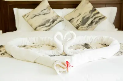 two towels shaped like swans on a bed at Blue Skyline Hotel in Patong Beach
