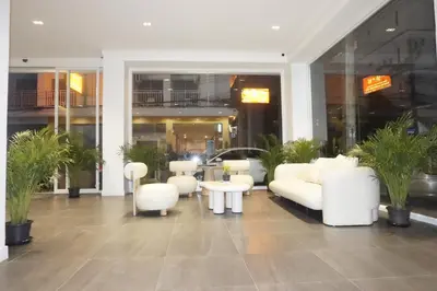 a lobby with white furniture and plants in a building at Blue Skyline Hotel in Patong Beach