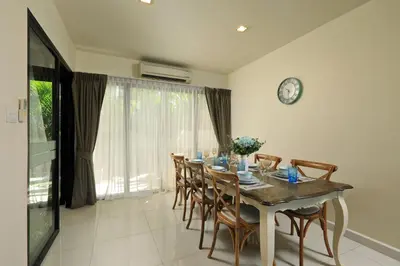 a dining room table with chairs and a clock on the wall at 3bdr Townhouse Laguna Park by CapitalPro 131 in Phuket Town