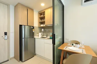 a kitchen with a stainless steel refrigerator and a table at Bangtao beach Cozy apartments by Capitalpro in Phuket Town