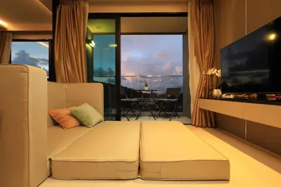 a living room with a couch and a large window at 1 bdr Sea view Apartment in Mida Surin Beach by Capital Pro in Phuket Town