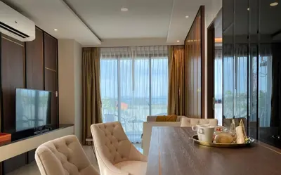 a living room with a dining table and a television at 2 bdr Apartment in Mida Grande Surin Beach by CapitalPro in Phuket Town