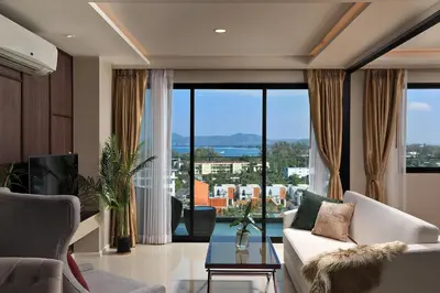 a living room with a couch and a large window at 3bdr SeaView Apartment in Surin Beach by Capital Pro in Phuket Town
